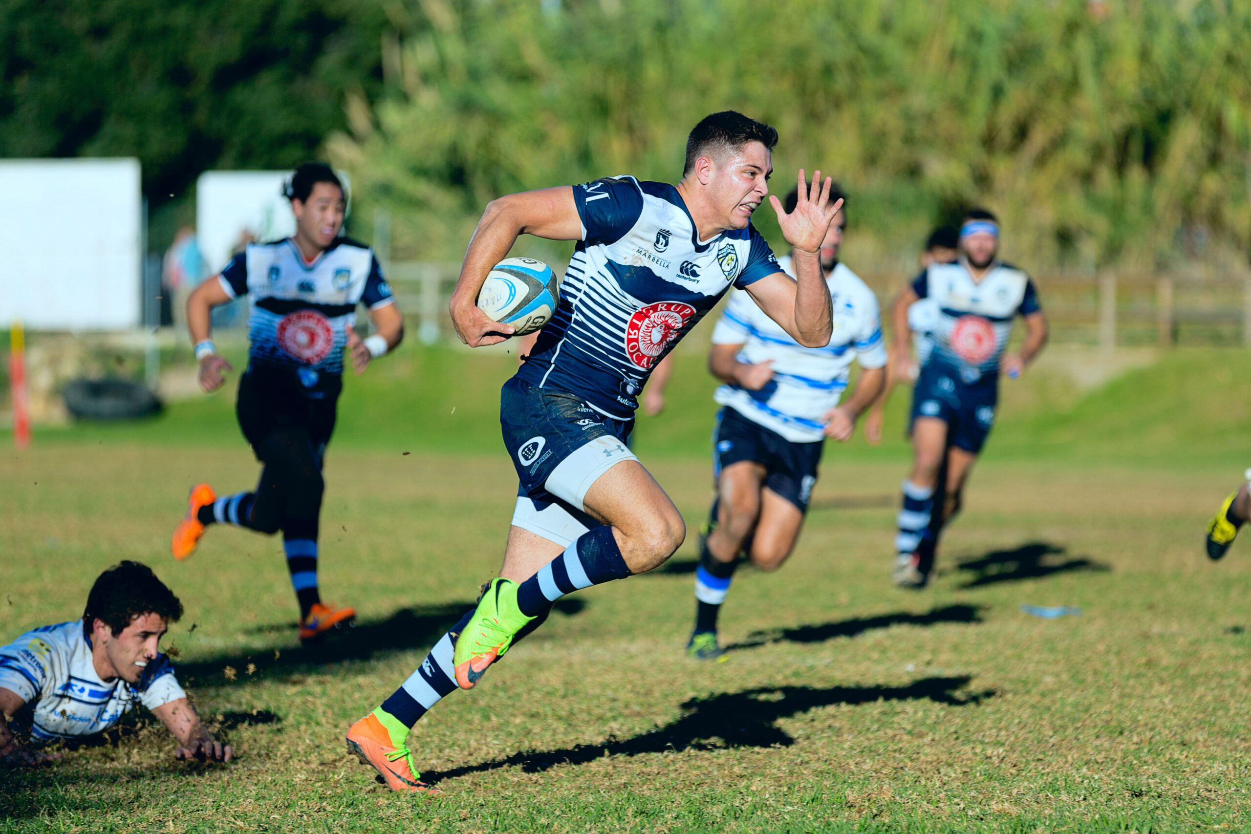 Image de rugbyman qui court dans l'herbe. C'est un club sportif