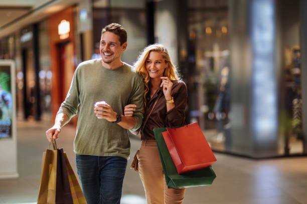 C'est un homme et une femme qui font les soldes, ils ont des sac à la main