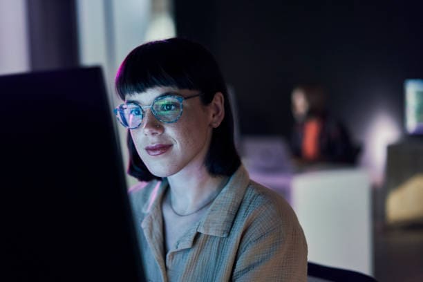 Image d'une femme qui regarde son ordinateur. Elle regarde peut-être un logiciel en mode SaaS