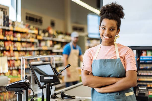 Femme souriante en face d'une caisse enregistreuse professionnelle