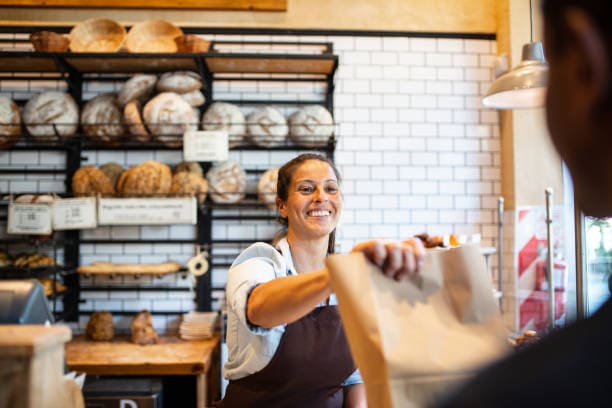 Photo de 2 personnes qui sont dans une boulangerie. La caissière a utilisé une caisse enregistreuse boulangerie