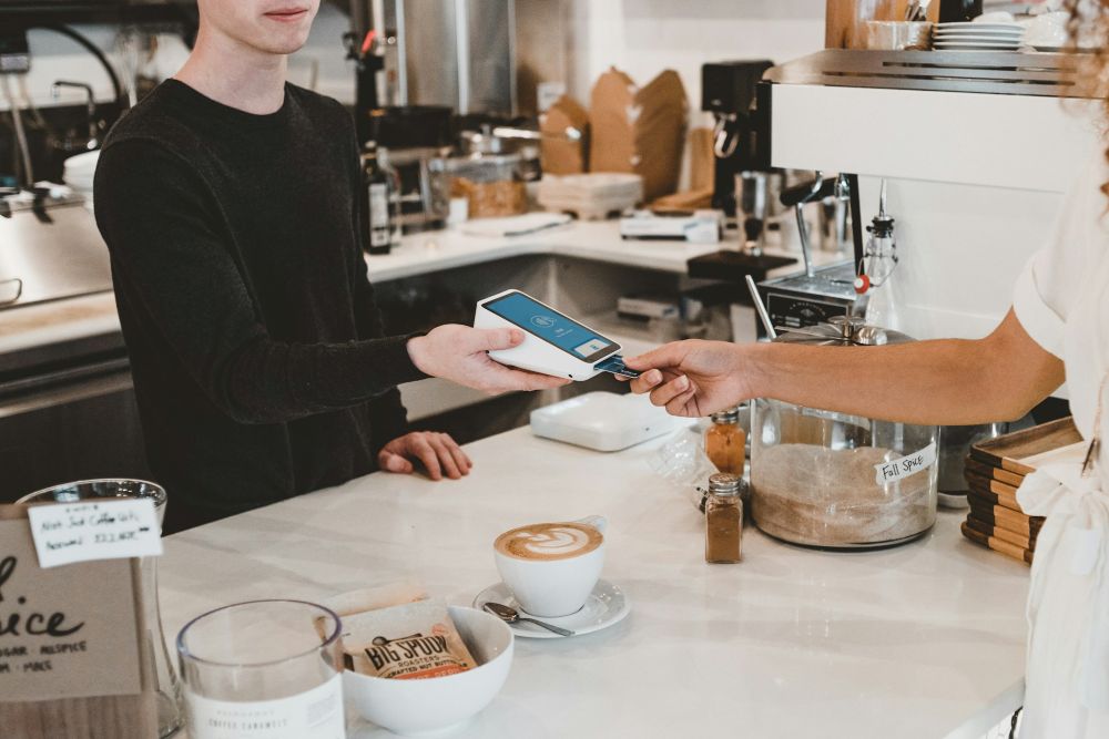 vendeur qui encaisse un client sur un pax mobile en coffee shop