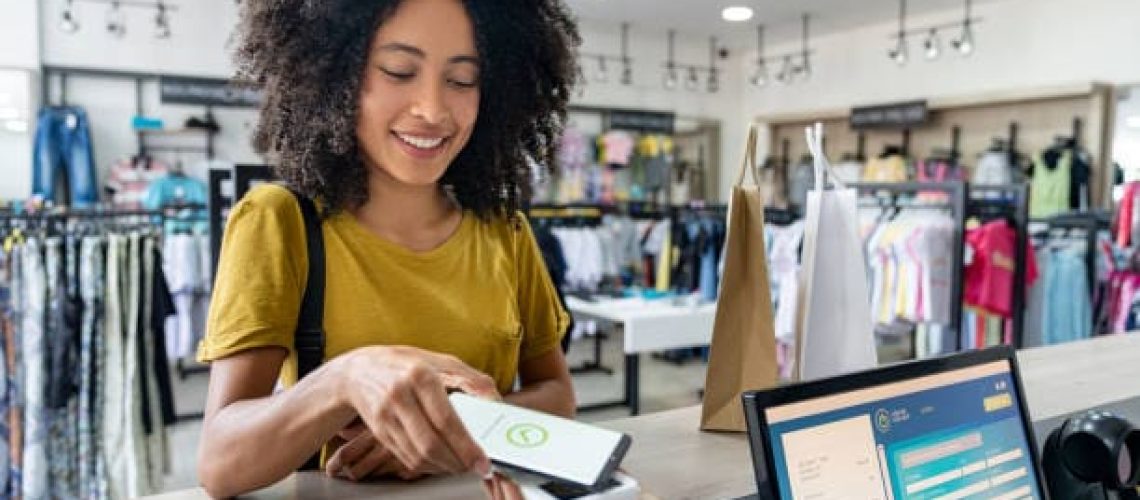 une femme qui paye avec son téléphone et une autre dame qui est derrière une caisse enregistreuse