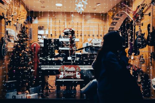 Femme devant la vitrine d'un magasin d'instruments de musique à Noël